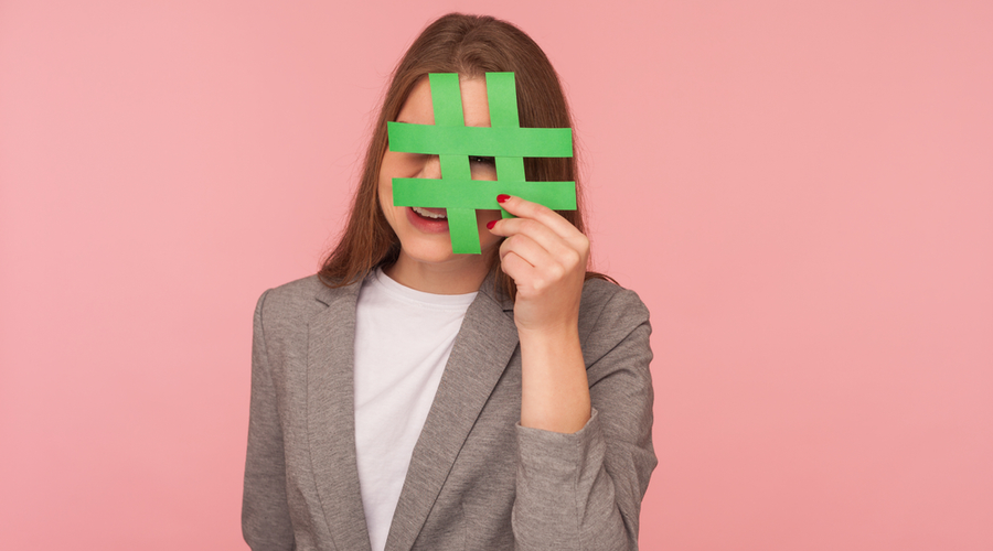 Woman holding hashtag over face against pink background